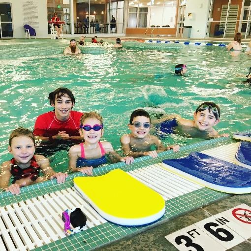 Four children and a lifeguard in the pool learning to swim